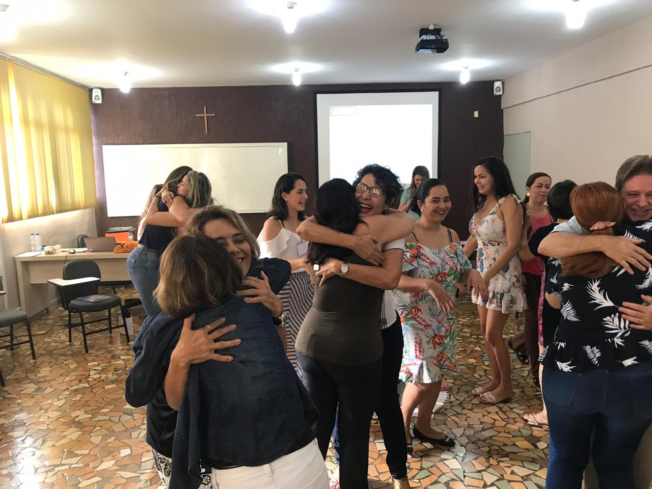 Participantes se abraçando durante vivência de CNV